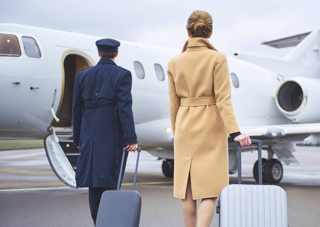 Professional chauffeur assisting passenger with luggage beside private jet