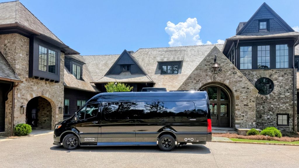 Black luxury passenger van parked outside a large estate